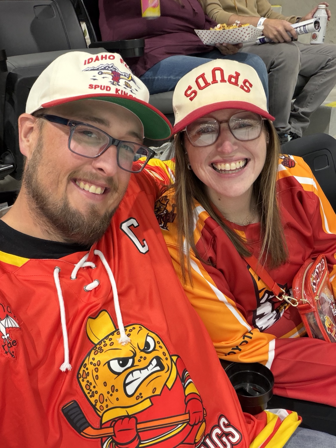 Tyson and Cherae Edwards wearing Spud Kings jerseys and hats at a hockey game